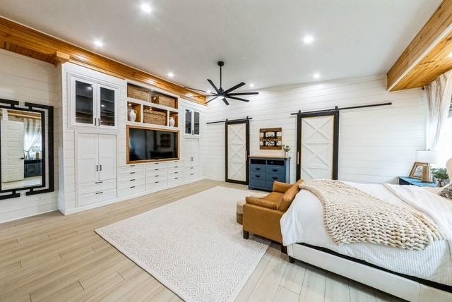 209 Horse Shoe Trl, Angleton, TX 77515 - bedroom with a barn door, wood finished floors, recessed lighting, and wooden walls