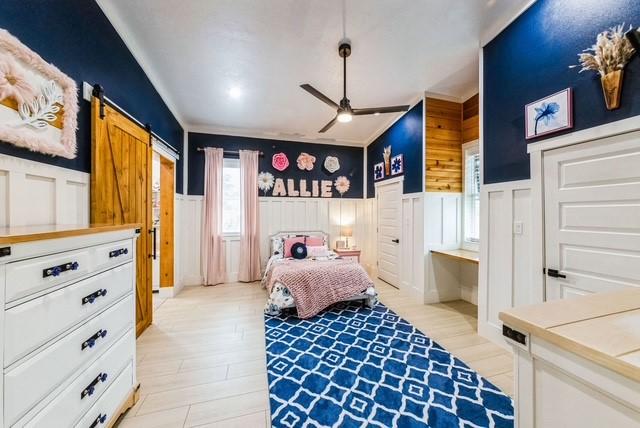 209 Horse Shoe Trl, Angleton, TX 77515 - bedroom with a wainscoted wall, a barn door, and light wood-type flooring
