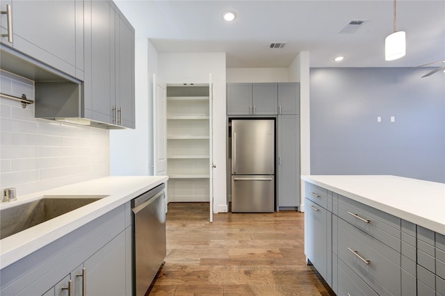 8964 Zurcher Ln, Houston, TX 77080 - kitchen featuring gray cabinets, stainless steel appliances, light wood-style floors, tasteful backsplash, and light countertops