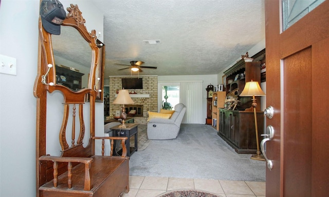 12662 Hackberry Dr, Willis, TX 77318 - living area with light carpet, light tile patterned floors, a brick fireplace, ceiling fan, and a textured ceiling