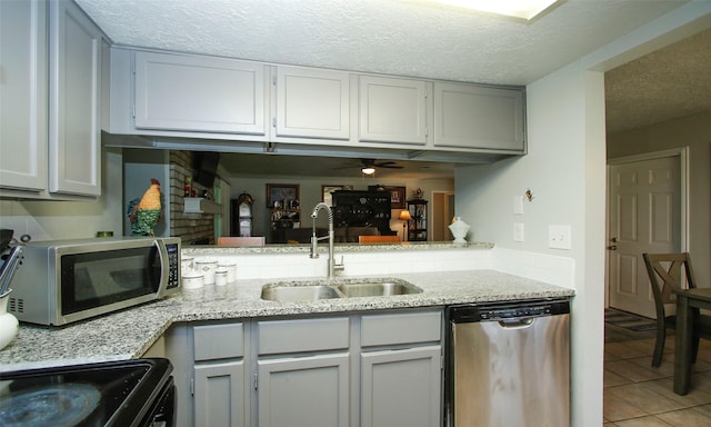 12662 Hackberry Dr, Willis, TX 77318 - kitchen featuring stainless steel appliances, a sink, a textured ceiling, light tile patterned floors, and a ceiling fan