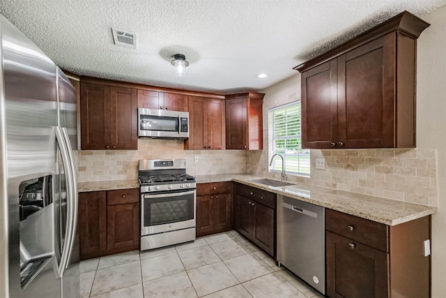 2738 Kettle Run, Sugar Land, TX 77479 - kitchen featuring stainless steel appliances, a sink, tasteful backsplash, light tile patterned floors, and a textured ceiling