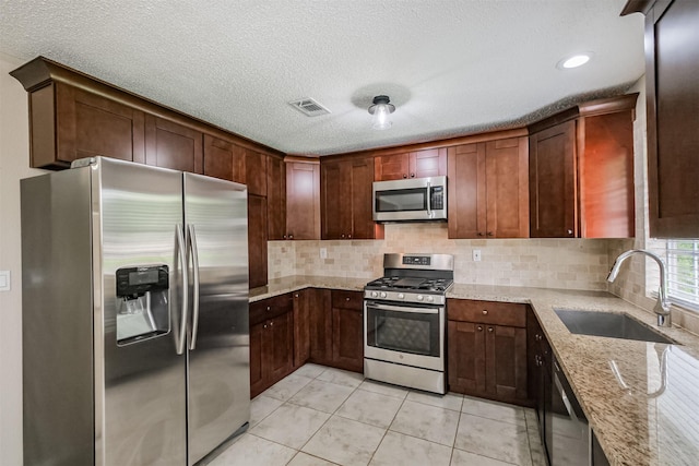 2738 Kettle Run, Sugar Land, TX 77479 - kitchen featuring appliances with stainless steel finishes, a sink, light stone counters, decorative backsplash, and a textured ceiling