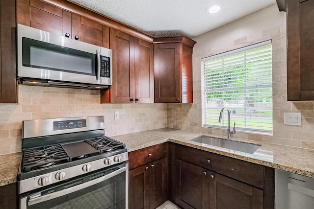 2738 Kettle Run, Sugar Land, TX 77479 - kitchen featuring appliances with stainless steel finishes, a sink, tasteful backsplash, light stone countertops, and a textured ceiling