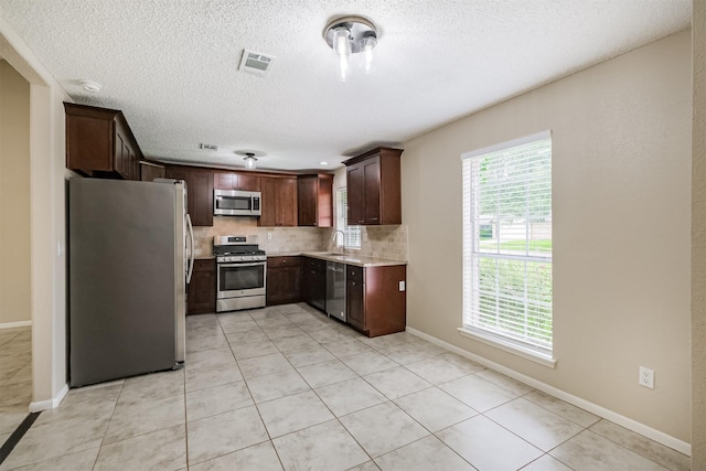 2738 Kettle Run, Sugar Land, TX 77479 - kitchen with stainless steel appliances, tasteful backsplash, a textured ceiling, baseboards, and light tile patterned flooring
