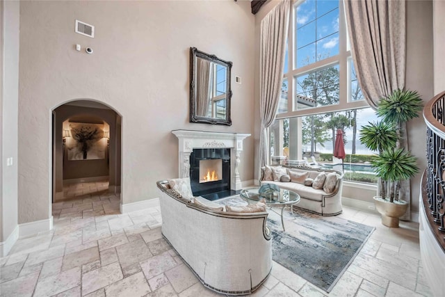 4510 Siandra Creek Ct, Spring, TX 77386 - living room with stone tile flooring, a towering ceiling, arched walkways, a premium fireplace, and baseboards