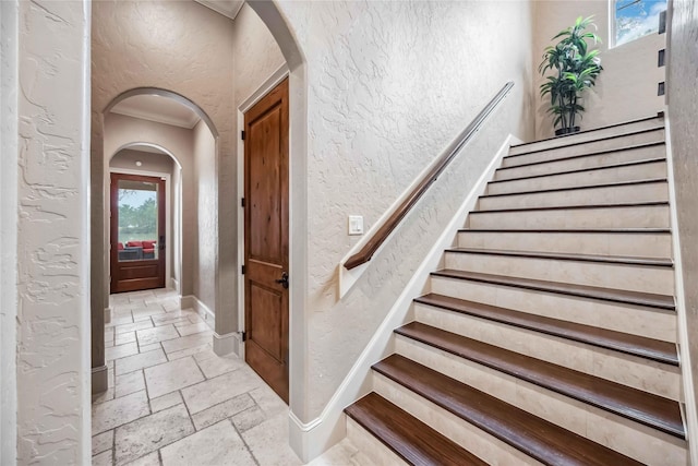 4510 Siandra Creek Ct, Spring, TX 77386 - staircase with stone tile floors, a textured wall, arched walkways, baseboards, and ornamental molding