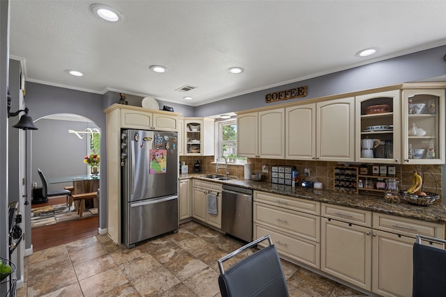 918 Hollow Tree St, La Porte, TX 77571 - kitchen with appliances with stainless steel finishes, a sink, cream cabinetry, arched walkways, and glass insert cabinets