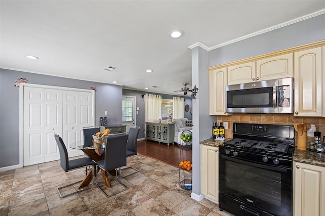 918 Hollow Tree St, La Porte, TX 77571 - kitchen featuring stainless steel microwave, black range with gas cooktop, cream cabinets, baseboards, and decorative backsplash