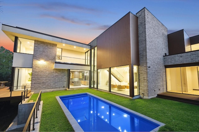 11206 Tyne Ct, Houston, TX 77024 - back of house at dusk with a balcony, a yard, an outdoor pool, and area for grilling