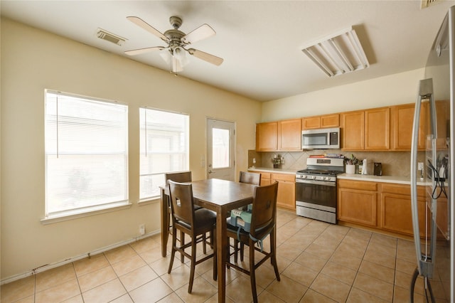23610 Youpon Lake Ln, Spring, TX 77373 - kitchen with stainless steel appliances, tasteful backsplash, light countertops, ceiling fan, and light tile patterned floors