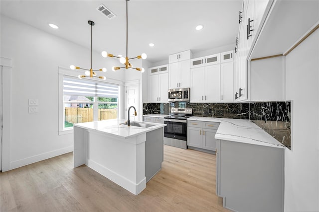 4902 Higgins St B, Unit A, Houston, TX 77033 - kitchen featuring appliances with stainless steel finishes, a sink, a chandelier, light wood finished floors, and tasteful backsplash