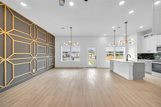 4902 Higgins St B, Unit A, Houston, TX 77033 - unfurnished living room featuring a chandelier, light wood-type flooring, recessed lighting, baseboards, and a sink
