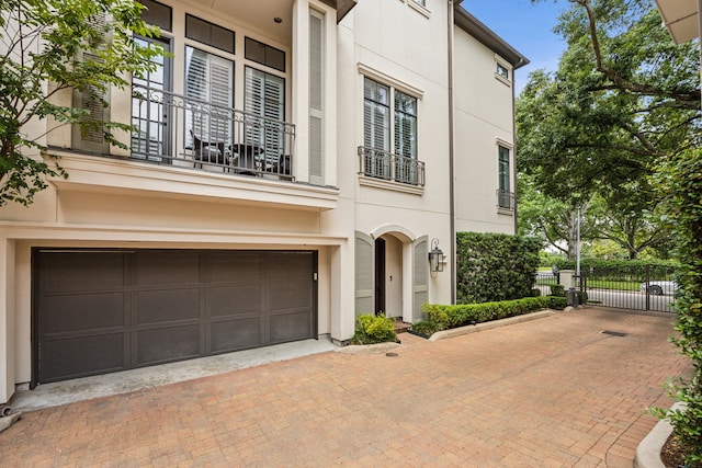 3202 Mid Ln, Houston, TX 77027 - view of front of house with stucco siding, an attached garage, decorative driveway, and a balcony