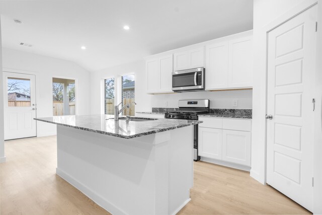 405 Amy St, Angleton, TX 77515 - kitchen featuring appliances with stainless steel finishes, a sink, dark stone countertops, light wood-style flooring, and white cabinets