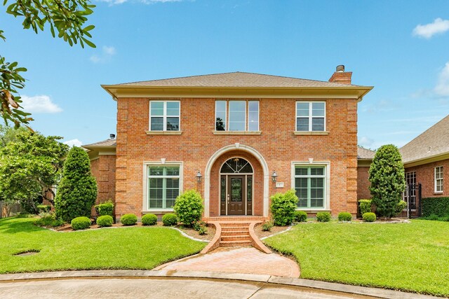 1 Heritage Oak Ct, Lake Jackson, TX 77566 - colonial-style house featuring a chimney, brick siding, a front yard, and roof with shingles