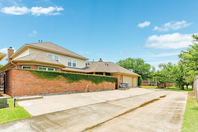 1 Heritage Oak Ct, Lake Jackson, TX 77566 - view of front of property featuring brick siding, driveway, an attached garage, a chimney, and cooling unit