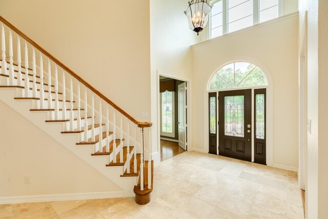 1 Heritage Oak Ct, Lake Jackson, TX 77566 - entryway with plenty of natural light, a high ceiling, stairway, a chandelier, and tile patterned floors