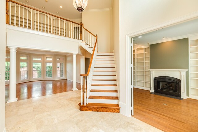 1 Heritage Oak Ct, Lake Jackson, TX 77566 - staircase with wood finished floors, a fireplace with flush hearth, crown molding, a high ceiling, and built in shelves