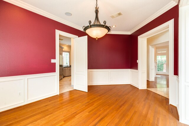 1 Heritage Oak Ct, Lake Jackson, TX 77566 - empty room featuring wood finished floors, a decorative wall, crown molding, and wainscoting