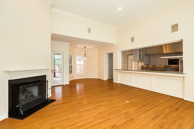 1 Heritage Oak Ct, Lake Jackson, TX 77566 - unfurnished living room featuring ornamental molding, light wood-style floors, a fireplace with raised hearth, baseboards, and recessed lighting