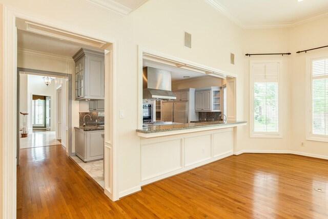 1 Heritage Oak Ct, Lake Jackson, TX 77566 - kitchen featuring gray cabinets, wall chimney range hood, wood finished floors, ornamental molding, and backsplash