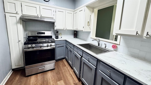 1105 S Main St, Highlands, TX 77562 - kitchen with under cabinet range hood, stainless steel gas stove, a sink, gray cabinets, and dark wood-style floors