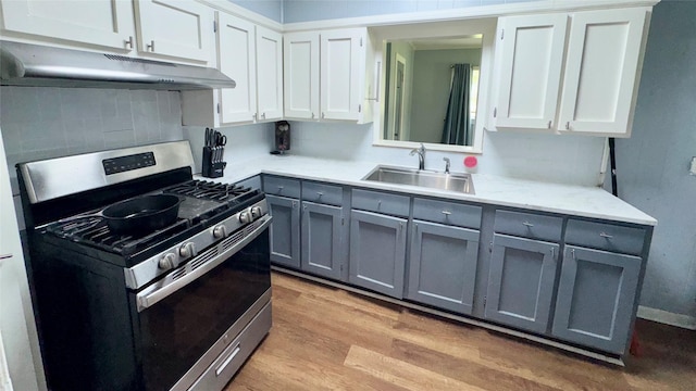 1105 S Main St, Highlands, TX 77562 - kitchen with gray cabinetry, stainless steel range with gas cooktop, a sink, under cabinet range hood, and light wood-style floors
