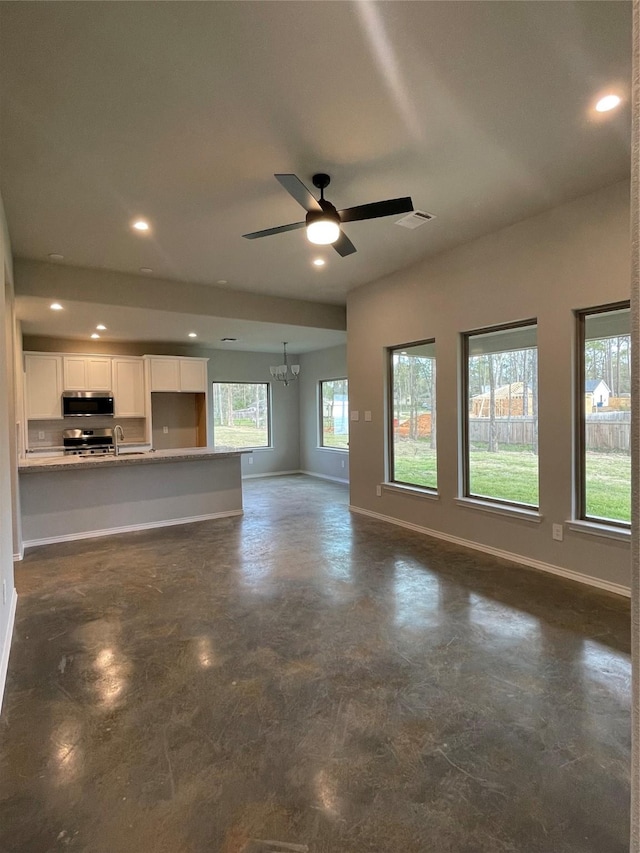 116 Indian Creek Cir, Willis, TX 77378 - unfurnished living room with baseboards, recessed lighting, ceiling fan, finished concrete floors, and a chandelier
