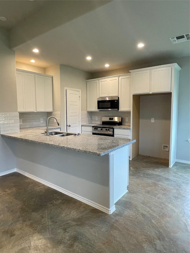 116 Indian Creek Cir, Willis, TX 77378 - kitchen with stainless steel appliances, a sink, white cabinets, a peninsula, and light stone countertops