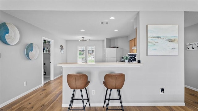 281 Fishermans Bend Dr, Point Blank, TX 77364 - kitchen with freestanding refrigerator, a kitchen breakfast bar, a peninsula, light wood finished floors, and baseboards