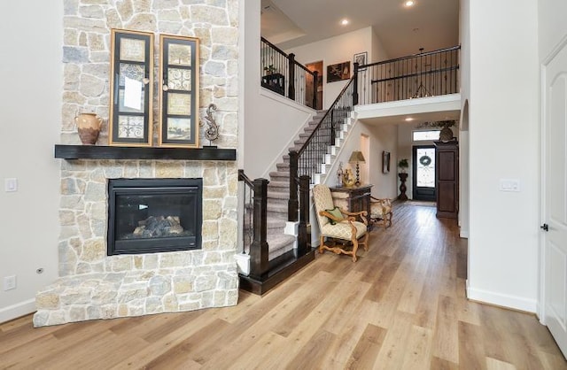 2038 Green Haven Ct, Missouri City, TX 77459 - living room with stairs, wood finished floors, baseboards, a towering ceiling, and a stone fireplace