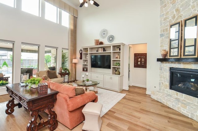 2038 Green Haven Ct, Missouri City, TX 77459 - living area with a towering ceiling, light wood finished floors, a ceiling fan, a fireplace, and baseboards