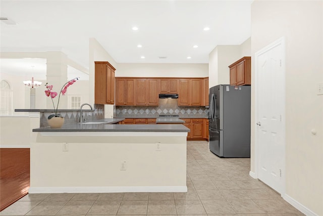 11108 Dawson Rd, Pearland, TX 77584 - kitchen featuring freestanding refrigerator, a peninsula, a sink, under cabinet range hood, and decorative backsplash