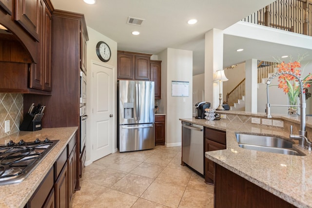 10518 Kicking Horse Pass, Cypress, TX 77433 - kitchen with stainless steel appliances, a sink, decorative backsplash, light stone counters, and dark brown cabinets