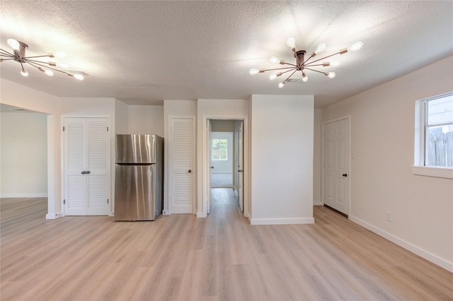 4914 Pershing St, Houston, TX 77033 - spare room with a chandelier, light wood finished floors, baseboards, and a textured ceiling