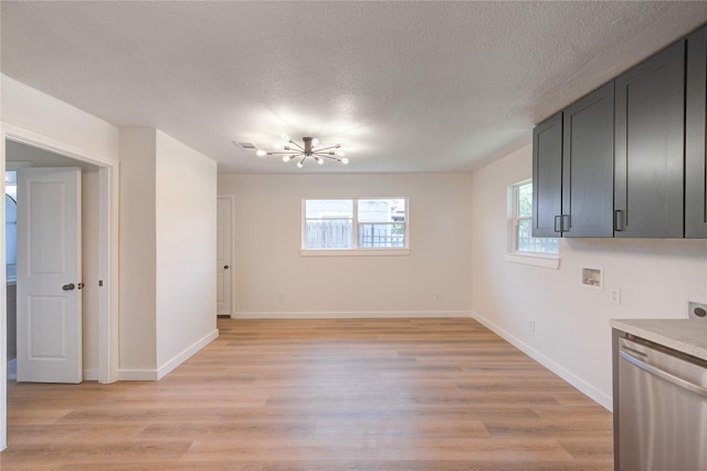 4914 Pershing St, Houston, TX 77033 - unfurnished dining area with a chandelier, healthy amount of natural light, light wood-style flooring, baseboards, and a textured ceiling