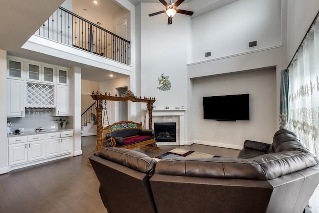 14303 Paseo Marbella Dr, Cypress, TX 77433 - living room featuring a bar, a towering ceiling, a ceiling fan, dark wood-type flooring, and a tile fireplace