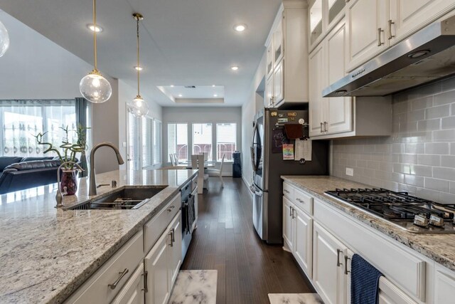 14303 Paseo Marbella Dr, Cypress, TX 77433 - kitchen featuring under cabinet range hood, a sink, appliances with stainless steel finishes, open floor plan, and light stone countertops
