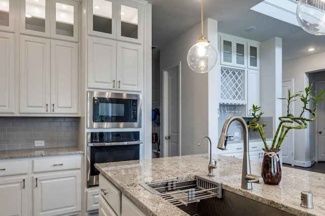 14303 Paseo Marbella Dr, Cypress, TX 77433 - kitchen featuring stainless steel oven, built in microwave, white cabinetry, decorative light fixtures, and a sink