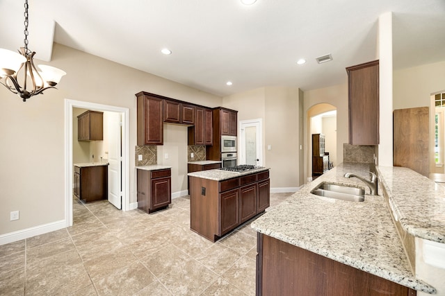 42 Brookefield Cir, Magnolia, TX 77355 - kitchen featuring a sink, stainless steel appliances, arched walkways, backsplash, and a chandelier