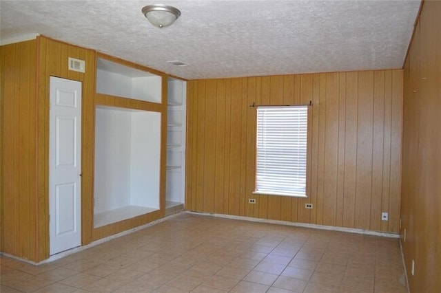 13907 Nitida St, Houston, TX 77045 - spare room with wood walls, a textured ceiling, and baseboards