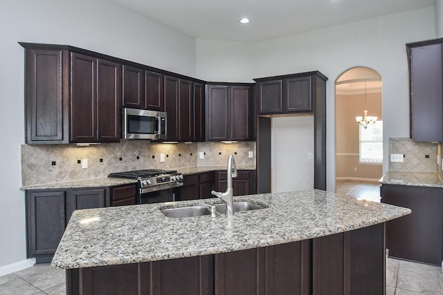 11819 Eagle Ridge Dr, Mont Belvieu, TX 77535 - kitchen featuring appliances with stainless steel finishes, a sink, dark brown cabinetry, light stone counters, and baseboards