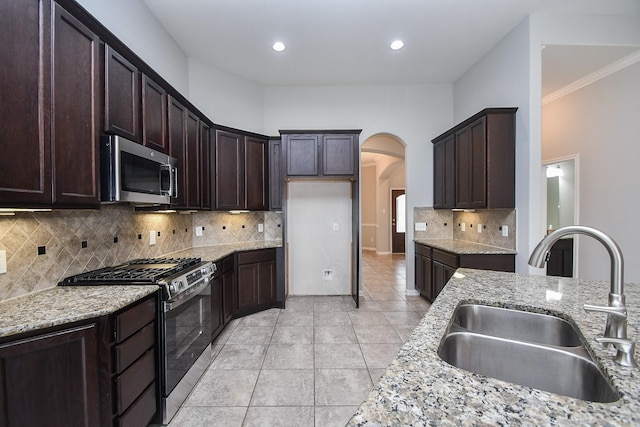 11819 Eagle Ridge Dr, Mont Belvieu, TX 77535 - kitchen featuring stainless steel appliances, a sink, arched walkways, light stone countertops, and ornamental molding