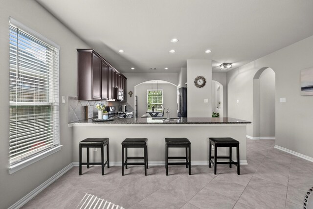 2525 Galley Ridge Dr, La Marque, TX 77568 - kitchen featuring arched walkways, stainless steel appliances, a kitchen bar, a peninsula, and a sink