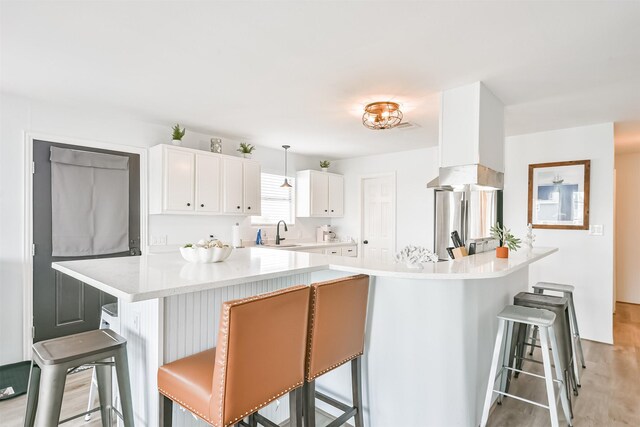 1004 20th St, Dickinson, TX 77539 - kitchen with a sink, a kitchen bar, freestanding refrigerator, white cabinetry, and light countertops