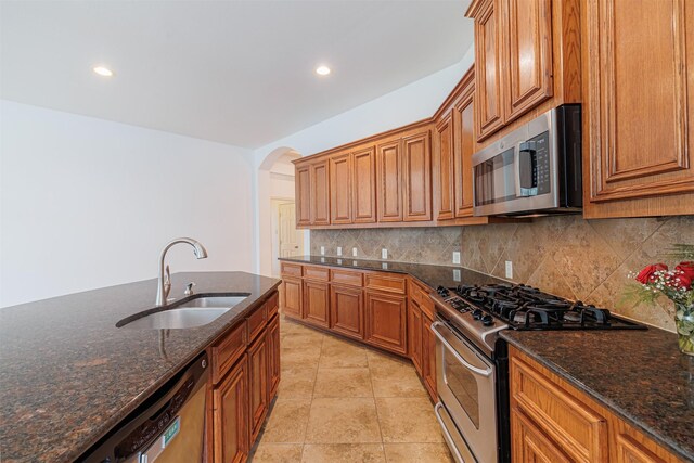 26122 Savory Springs Ln, Katy, TX 77494 - kitchen with appliances with stainless steel finishes, a sink, arched walkways, backsplash, and brown cabinets