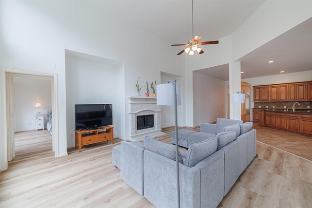 26122 Savory Springs Ln, Katy, TX 77494 - living area with light wood-style flooring, a fireplace, a towering ceiling, ceiling fan, and recessed lighting