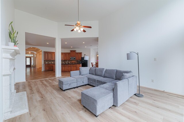 26122 Savory Springs Ln, Katy, TX 77494 - living area featuring arched walkways, ceiling fan, light wood-style flooring, a towering ceiling, and baseboards