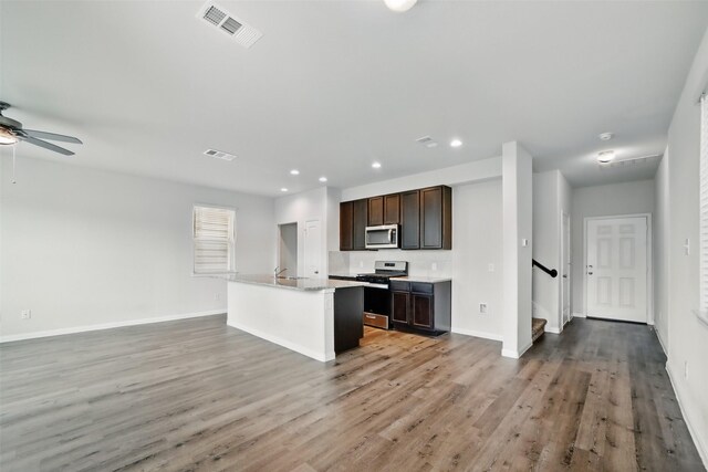 24851 Goldoni Dr, Katy, TX 77493 - kitchen with appliances with stainless steel finishes, ceiling fan, open floor plan, dark brown cabinetry, and light wood-style flooring